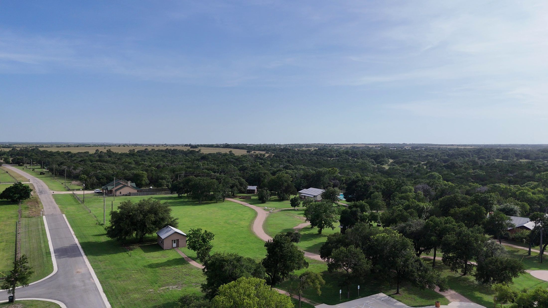 Aerial view of Camp Tahuaya: an open field, cabins, and oak woodland under a wide sky.