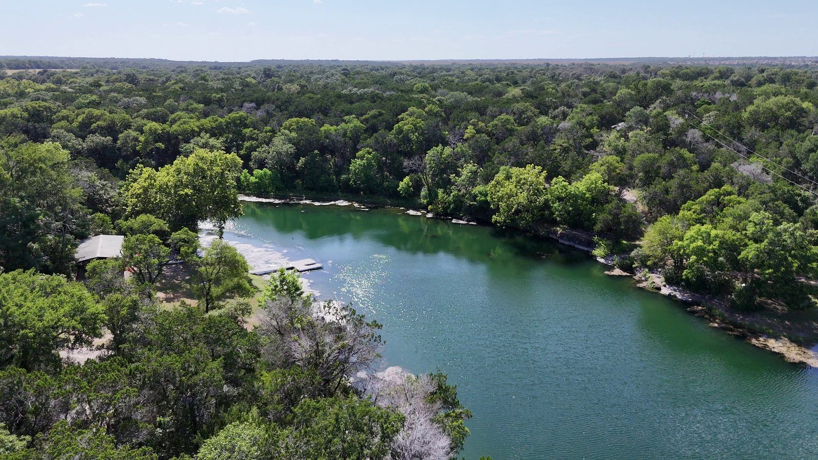 Aerial view of the spring-fed lake at Camp Tahuaya, with a dock and a pavilion on the shore.