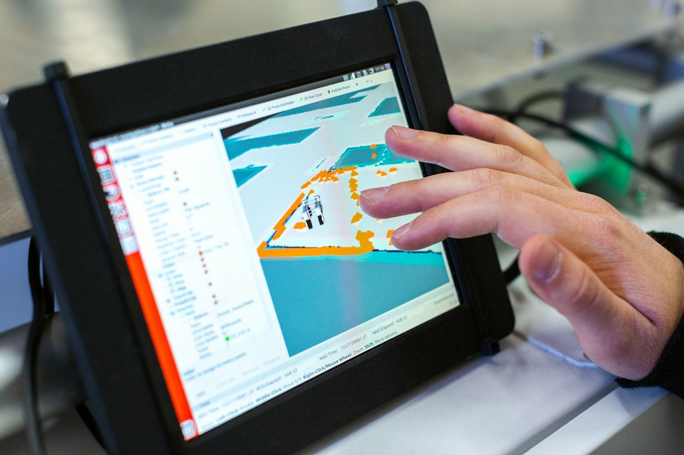 A hand works a ruggedized touchscreen showing a map.